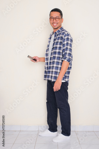 Full body portrait of a man holding cellphone with happy expression photo