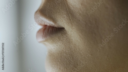 Concept of cosmetic skin care services. Macro shot of a woman's face. Lips of a young Asian woman, side view.