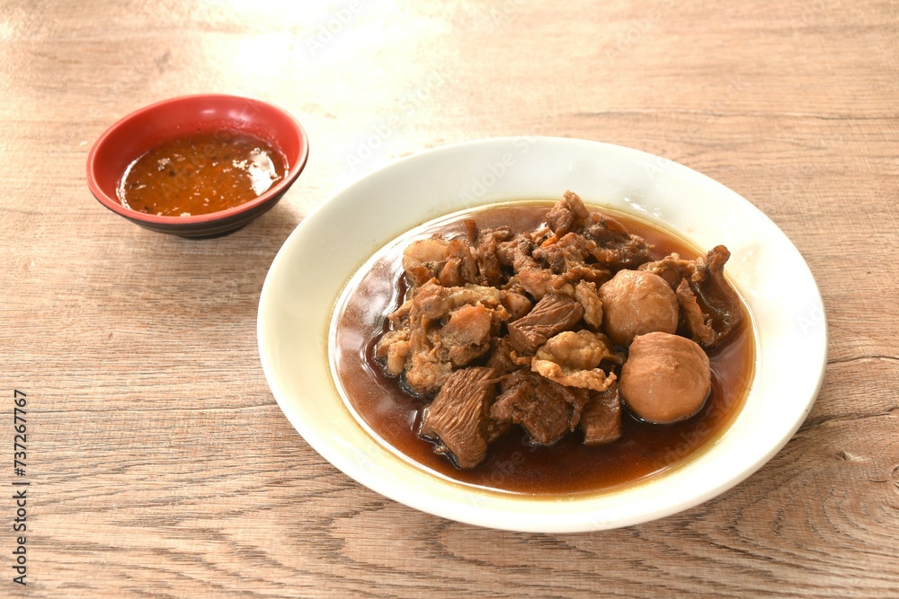 braised pork and meatball in herb brown soup on dish and spicy chili sauce braised pork and meatball in herb brown soup on dish and spicy chili sauce