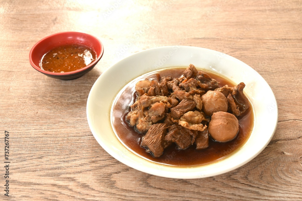 braised pork and meatball in herb brown soup on dish and spicy chili sauce 