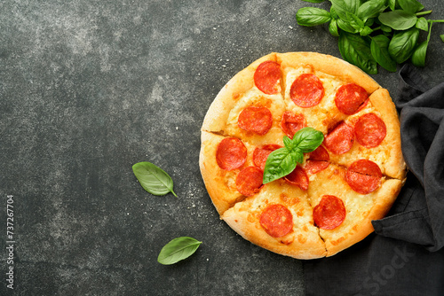 Pepperoni pizza. Traditional pepperoni pizza and cooking ingredients tomatoes basil on old concrete texture background table. Italian Traditional food. Top view. Mock up.