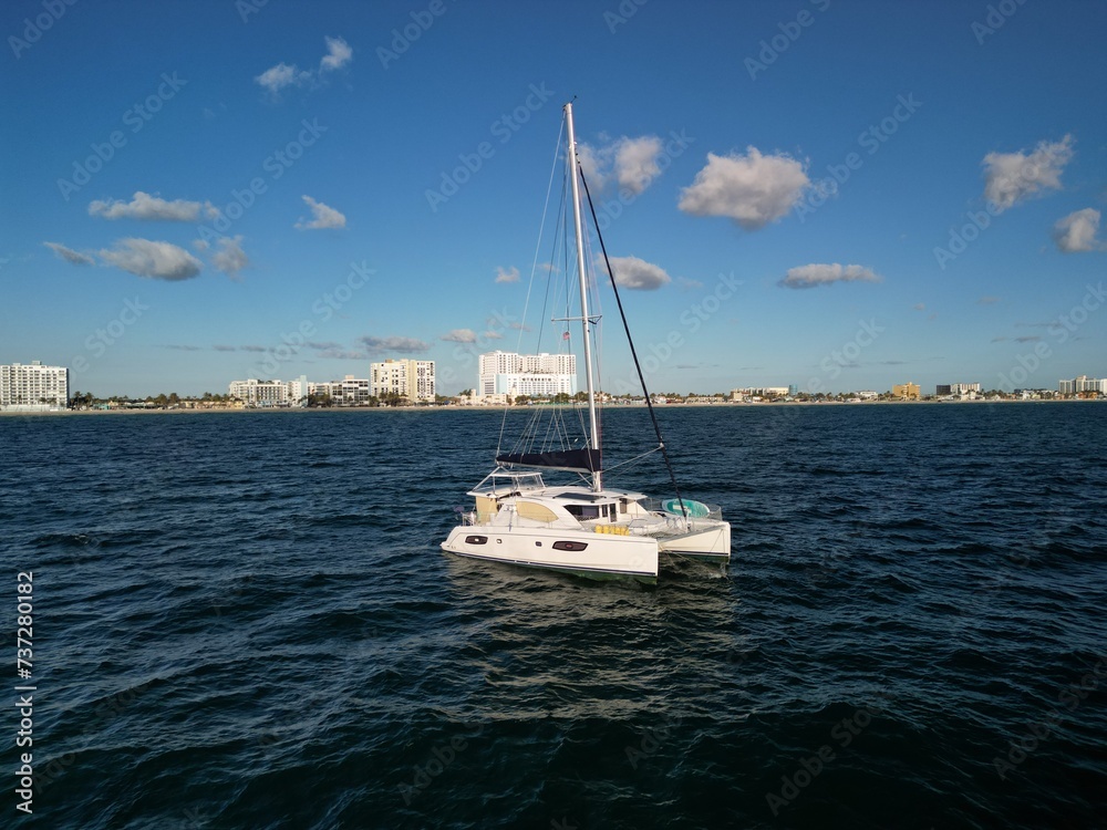 A catamaran sailboat anchored at sea on a calm ocean just off the coast of South Florida
