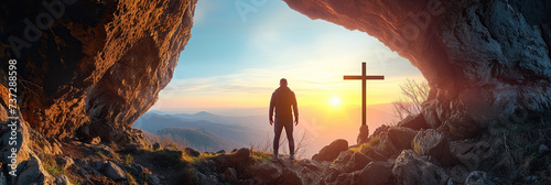 Figure standing in cave entrance, overlooking a cross at sunrise, representing hope, spirituality, resurrection, Easter, and contemplative peacefulness amidst natural beauty. photo