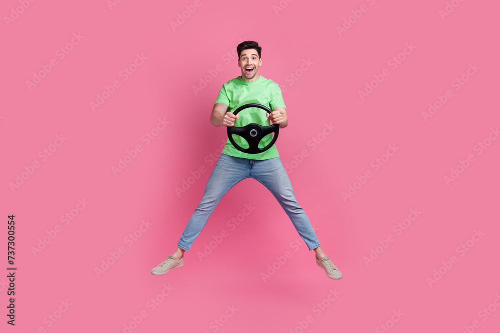 Full length size photo of young funky student learning on simulator hold steering wheel jumping air isolated on pink color background