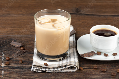 A glass of Irish cream liqueur, a cup of black coffee and coffee beans with chocolate.