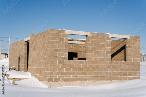 A brick building with a snowy facade is rising against the sky on a snowy slope