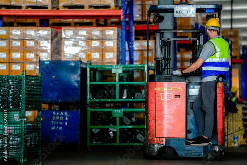 factory man driving forklift car working in distribution warehouse. factory worker teammates working beside stacks of cargo. Group of Diversity engineer factory people meeting.