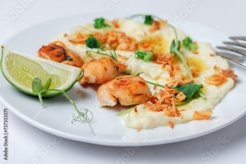 Scallops served with garnish mashed potatoes on the plate with fork and knife isolated on white background. Side View.