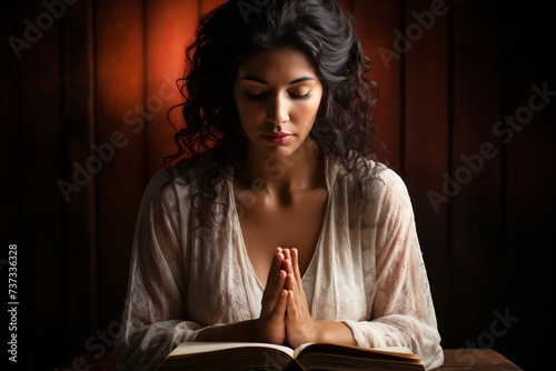 Praying woman with dark hair wearing white dress photo
