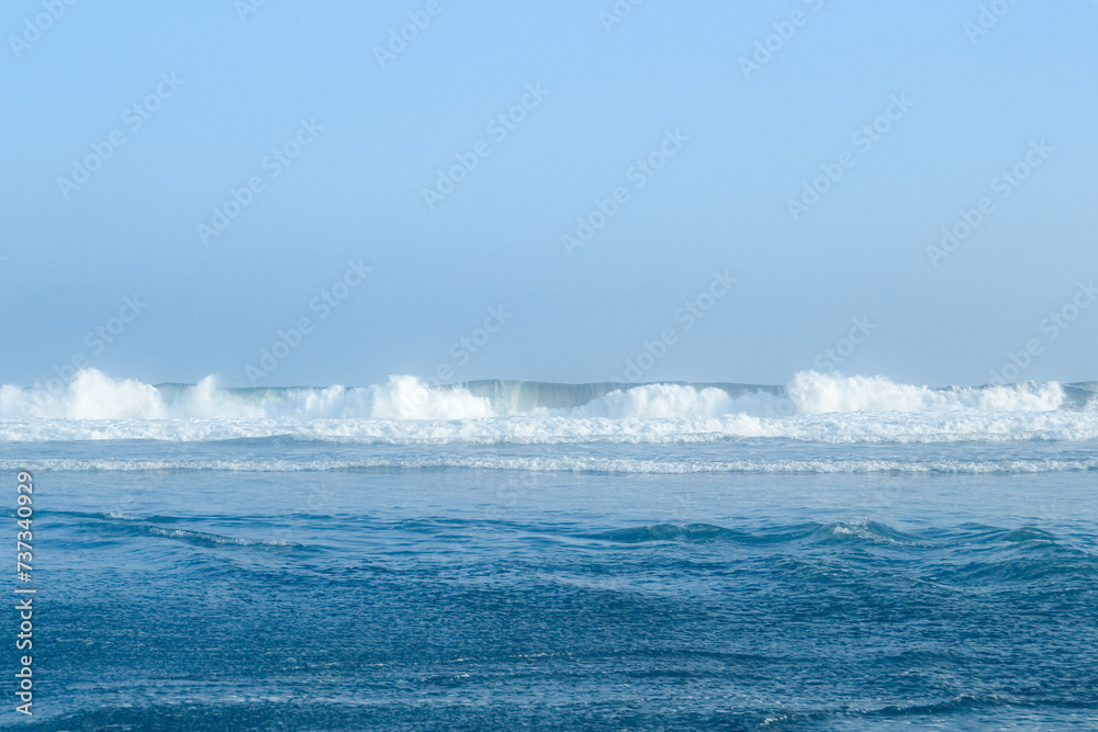 high waves in the sea off the southern island of Java with clear blue sky on the beach in the afternoon 