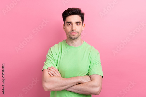 Portrait of confident young man folded arms wearing green t shirt looks confident at job interview isolated on pink color background