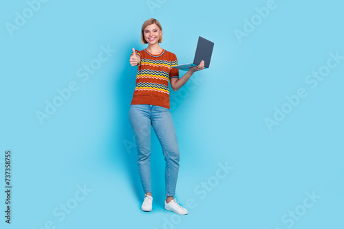 Full length photo of satisfied girl wear strited t-shirt holding laptop show you thumb up good work isolated on blue color background