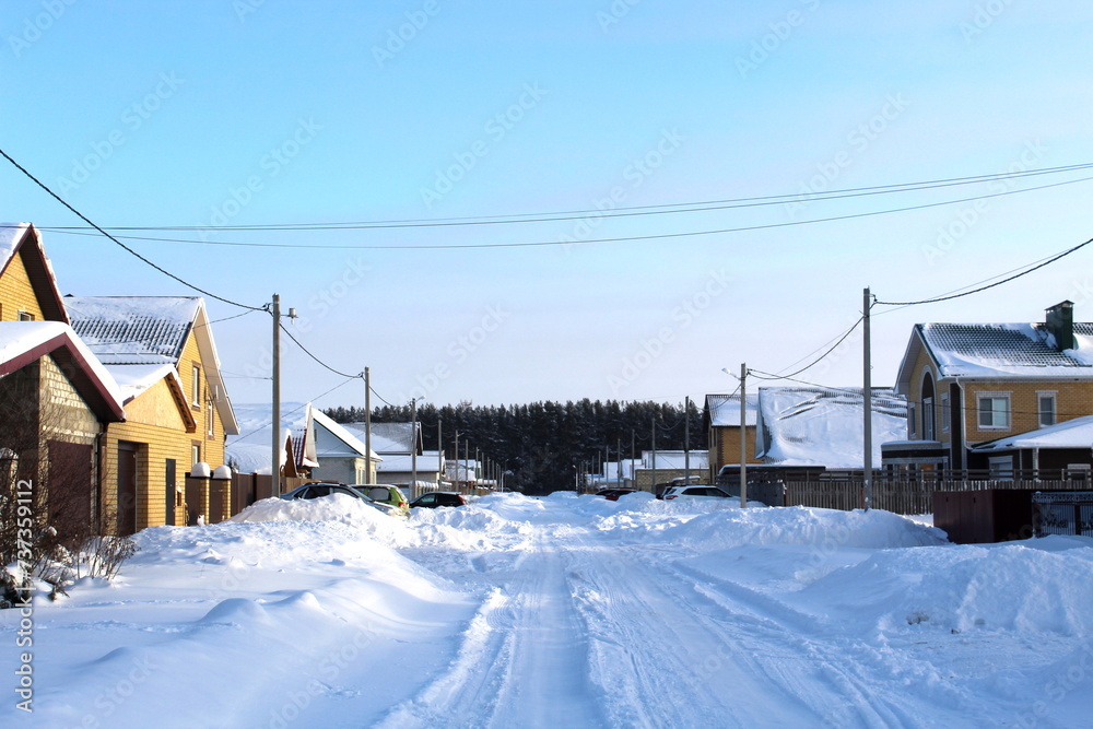 The village is covered with snow on a clear winter day.