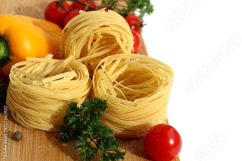Nest pasta with vegetables lies on a white cutting board.