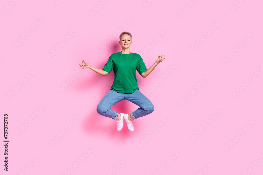 Full size photo of charming peaceful girl dressed green t-shirt levitating in meditation pose on retreat isolated on pink color background Full size photo of charming peaceful girl dressed green t-shirt levitating in meditation pose on retreat isolated on pink color background