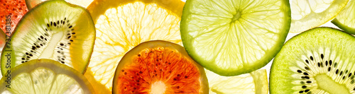 Slices of fruit lie on white. Juicy kiwi, figs, lime, orange and lemon in the light. Concept on the theme of food.