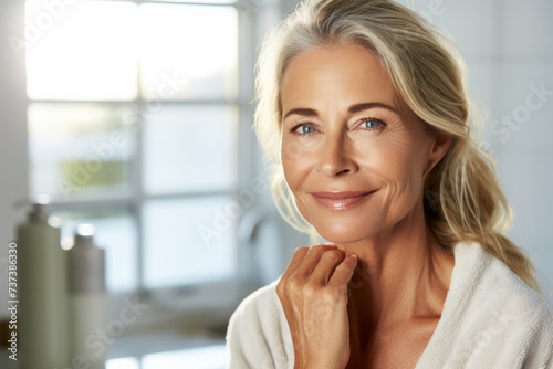 Gorgeous mid age adult 50 years old blonde woman standing in bathroom after shower with copyspace.