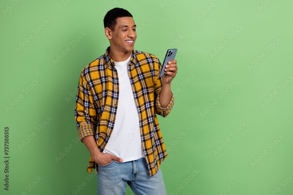Photo of young cheerful positive guy waiting for a girlfriend he invited date smartphone texting isolated over green color background Photo of young cheerful positive guy waiting for a girlfriend he invited date smartphone texting isolated over green color background