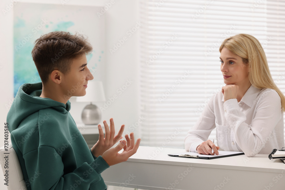 Psychologist working with teenage boy at table in office Psychologist working with teenage boy at table in office