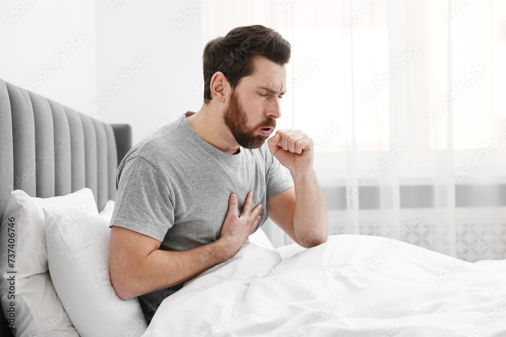 Sick man coughing on bed at home. Cold symptoms Sick man coughing on bed at home. Cold symptoms