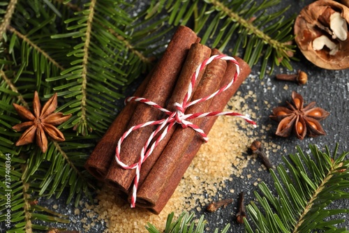 Different aromatic spices and fir branches on grey textured table, flat lay