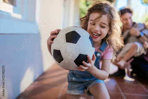 Joyful girl playing with a soccer ball with her family in the background photo