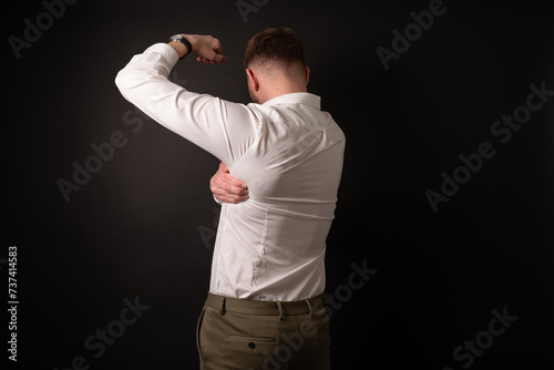 Business man in office attire having shoulder pain in l from poor working positions.