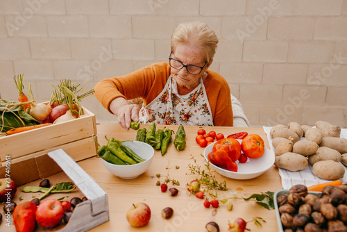 Elderly woman preparing fresh vegetables in kitchen photo