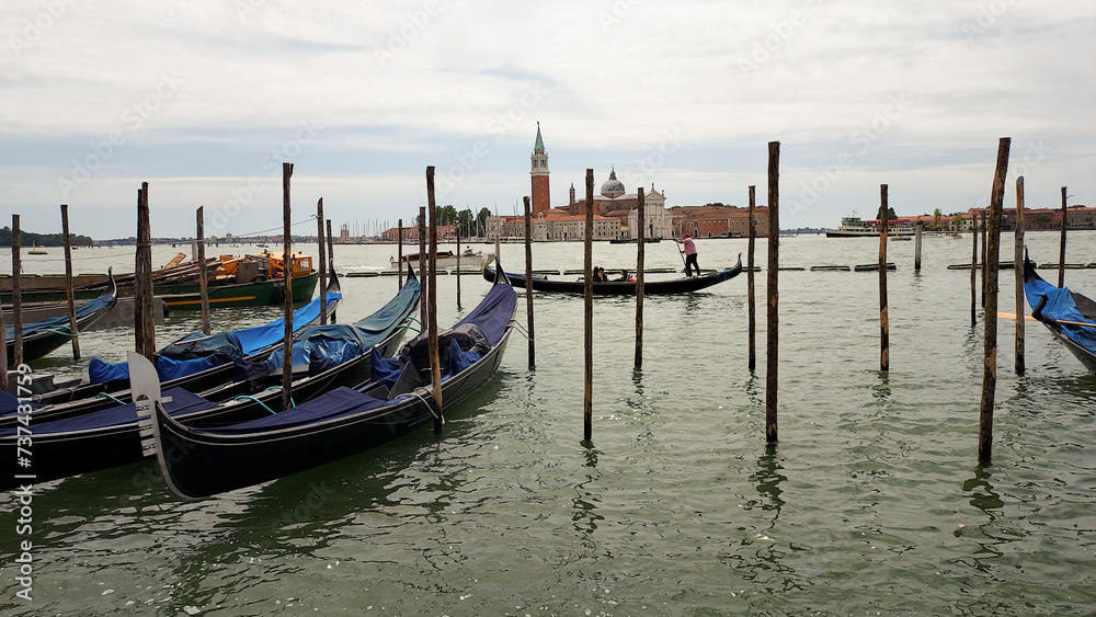 Venetian religious green lantern and gondolas docked by wooden mooring poles in Grand Canal with the Basilica Di Santa Maria Della Salute in background, near Piazza San Marco, Venice, Italy. 