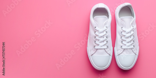 Stylish mock-up white sneakers pair isolated on a pastel pink background. 