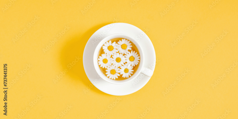 White chamomiles, cup of tea on yellow background. Herbal tea of chamomile flower. Chamomile tea concept. Flat lay, top view, copy space White chamomiles, cup of tea on yellow background. Herbal tea of chamomile flower. Chamomile tea concept. Flat lay, top view, copy space