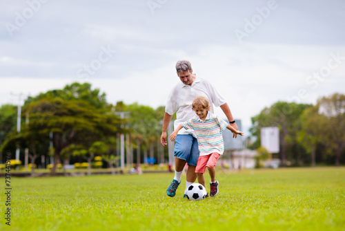 Father and son play football. Dad and kid run.