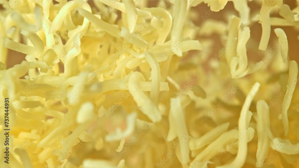 The grated cheese flies up and falls down. On an orange background. Filmed on a high-speed camera at 1000 fps. High quality FullHD footage