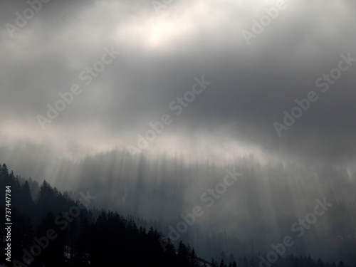 Foggy sunrise on Cross Mountain peak Monte croce sun rays passing through clouds in winter dolomites snow panorama val badia valley