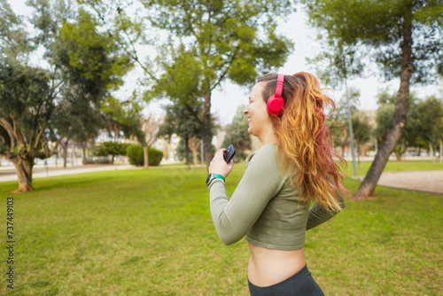 Cheerful woman running with smartphone and headphones