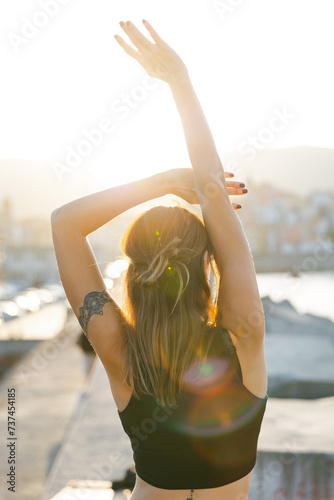 Young slim woman stretching arms on embankment near river photo