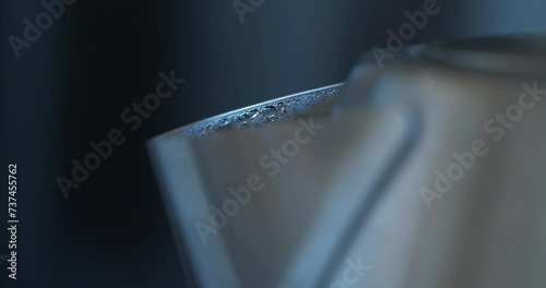 Water boils in metal kettle. Kettle shakes and splashes water. Steam comes out of kettle spout. Formation of steam and condensation, drops of water. Kettle heated water to 100 degrees Celsius photo