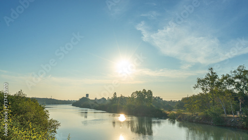 Image of the morning sun who had just risen above the horizon at the edge of a clear pond In the water there is a reflection of the sun. that is bringing light to the world Among the masses of various