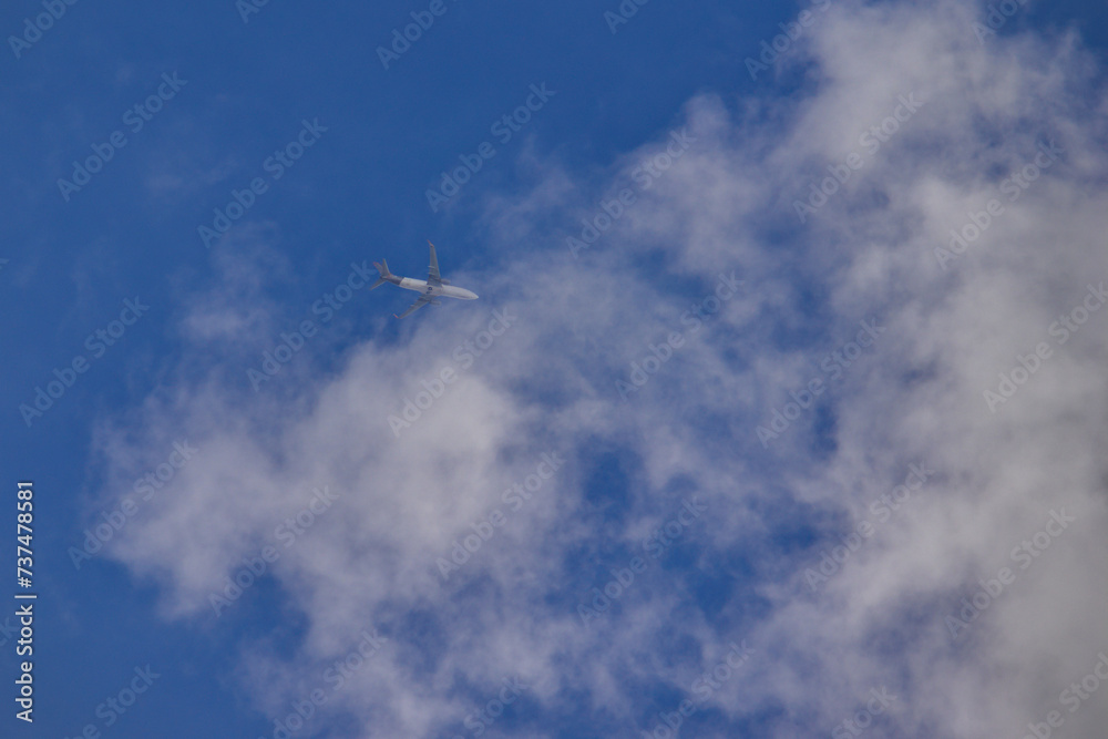 jet plane flying at high altitude among thin white clouds in a blue sky. jet plane flying at high altitude among thin white clouds in a blue sky.