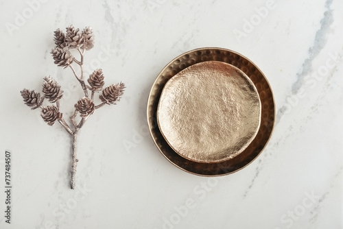 Two golden plates and a decorative golden branch with pine cones © tashka2000