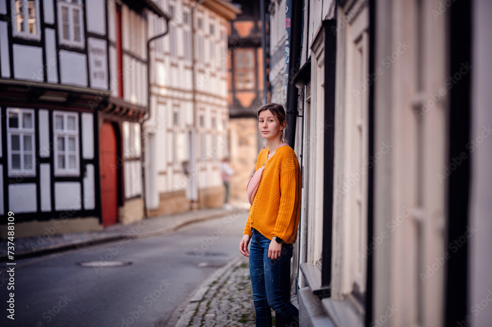 Young Woman in a Bright Sweater Leaning on an Old Town Street