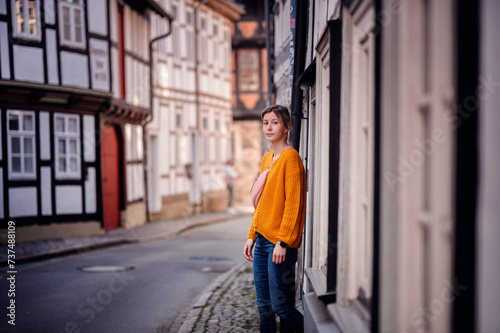 Young Woman in a Bright Sweater Leaning on an Old Town Street © Иванна Емельянова