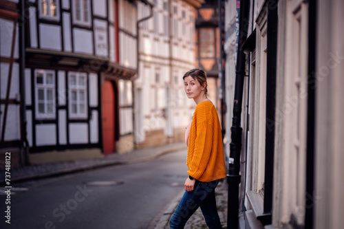 Young Woman in a Bright Sweater Leaning on an Old Town Street