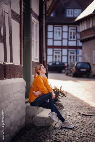Reflective Young Woman Sitting on Steps in Quaint European Street