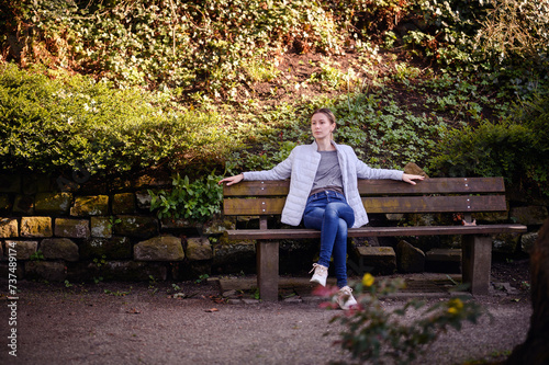 Relaxed Young Woman Stretching on a Park Bench Amidst Nature