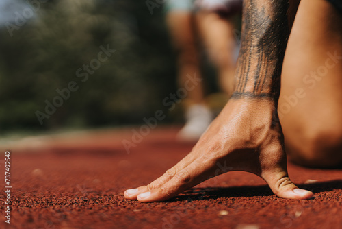Man preparing to run on a race track in the park. Sports man in a starting running position. Copy space.