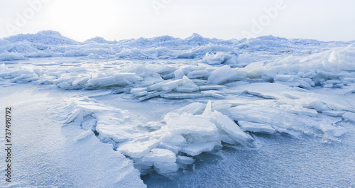Ice hummocks covered with snow. Panoramic landscape photo with coast of frozen Baltic Sea on cold winter day