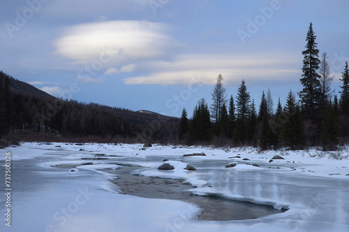 Icy river in a winter wonderland under a cloudy sky © Anna