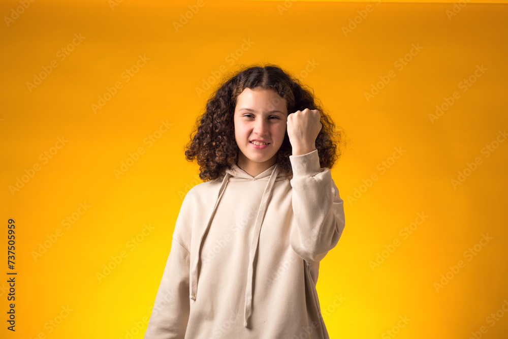 Enrage girl showing fist at camera on yellow background. Negative emotions concept Enrage girl showing fist at camera on yellow background. Negative emotions concept