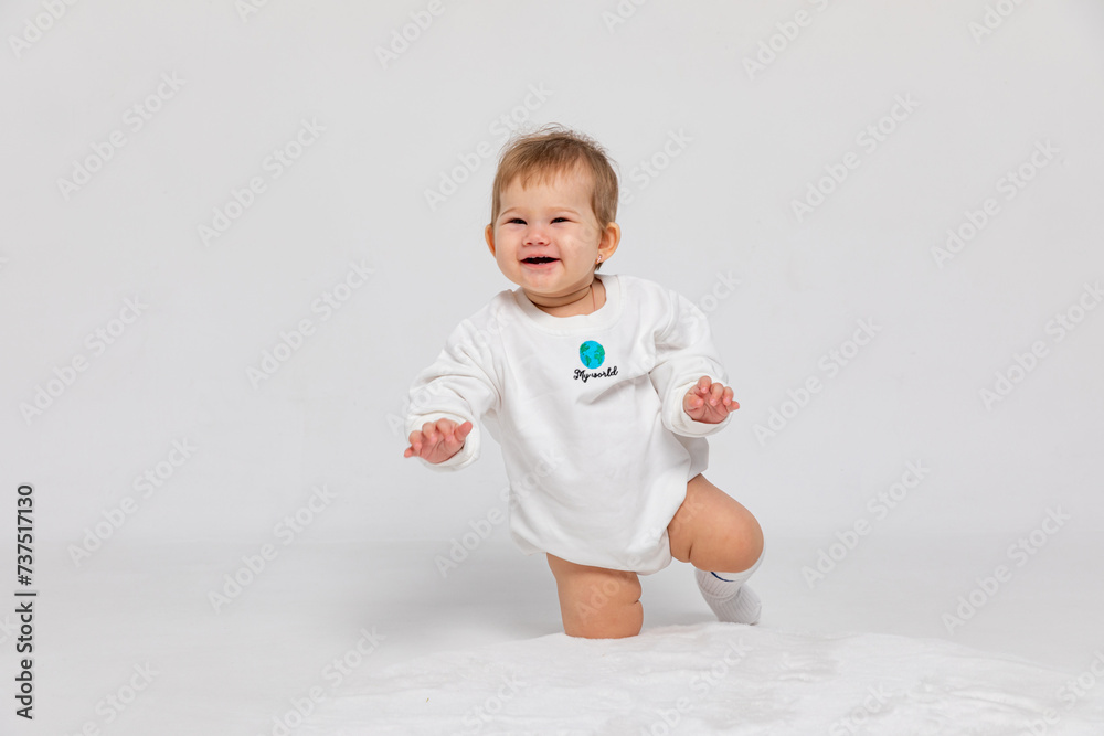 Portrait of a happy little newborn baby girl in a white bodysuit with inscription my world crawling on white background, save the planet. Earth day concept with copy space Portrait of a happy little newborn baby girl in a white bodysuit with inscription my world crawling on white background, save the planet. Earth day concept with copy space